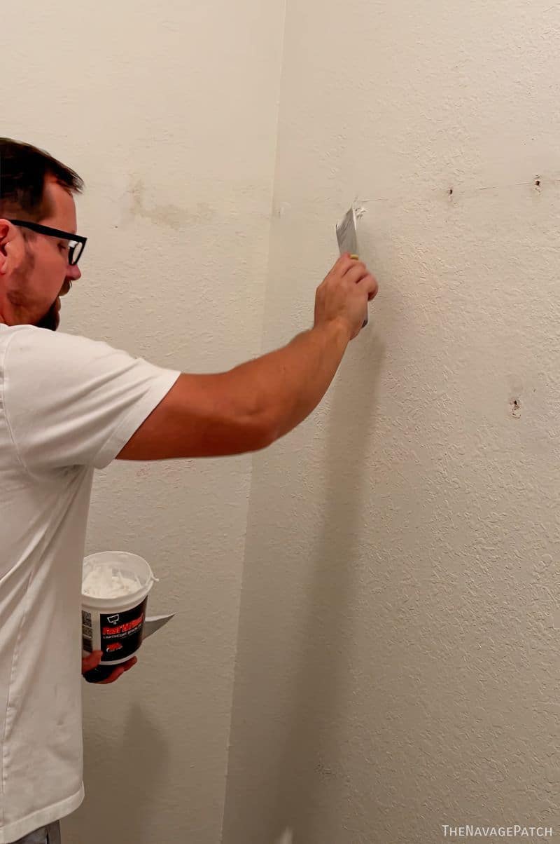 man repairing drywall holes in a closet