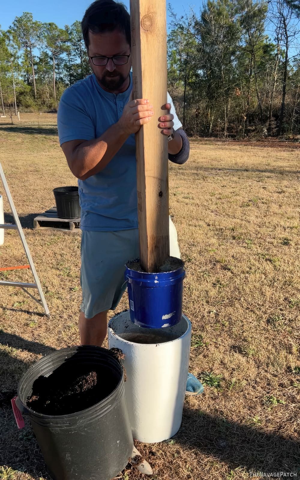 man putting a cedar post into a planter