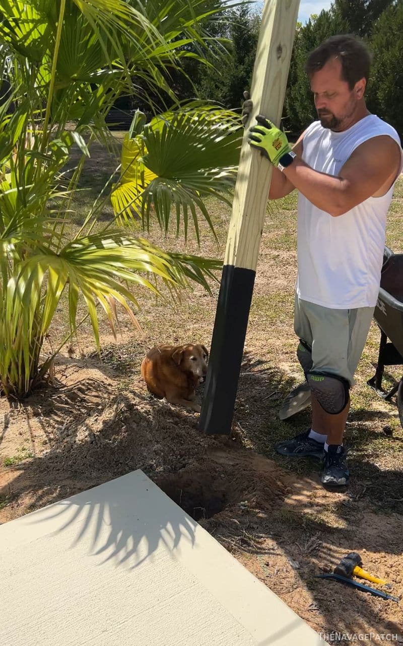 man putting a fence post into its hole