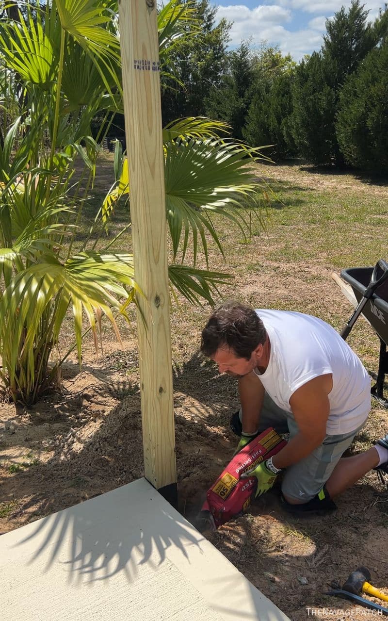 man putting concrete mix in a fence post hole