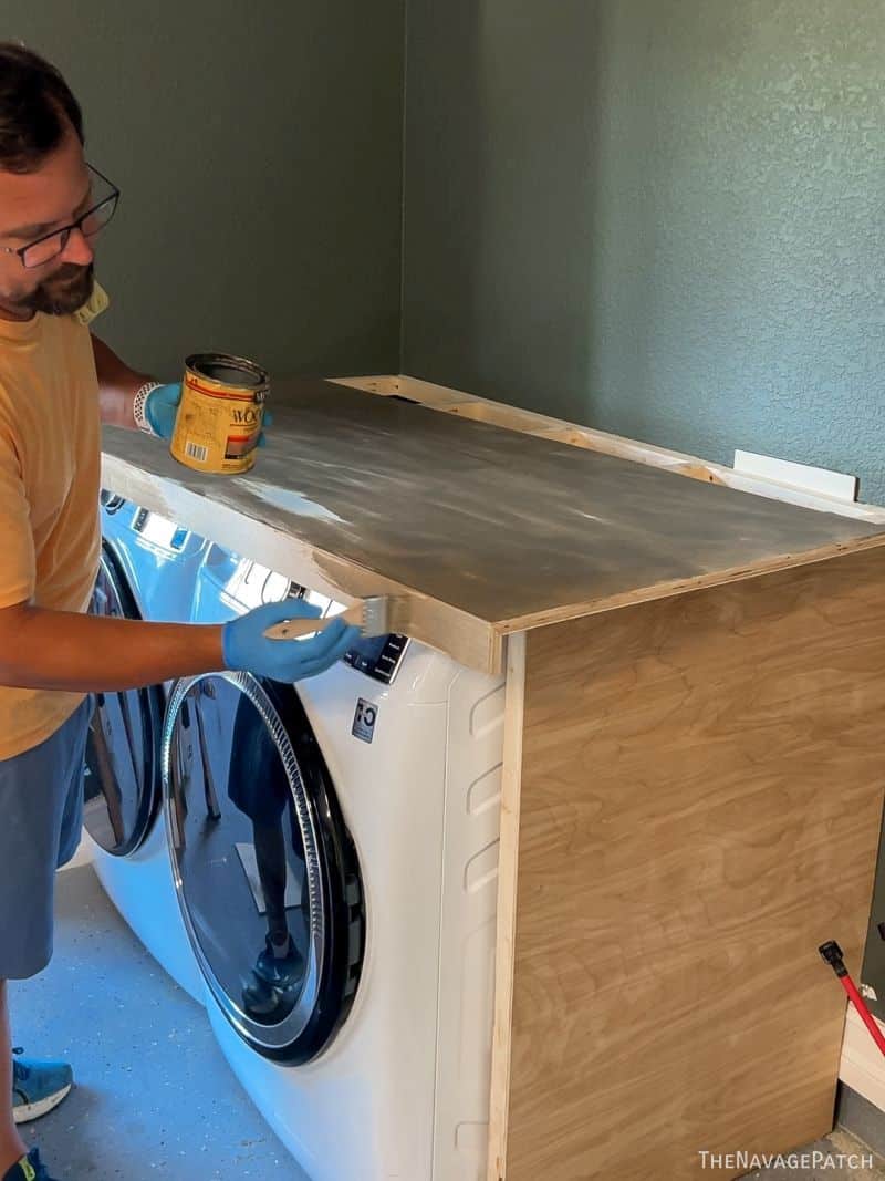 man staining a washer dryer enclosure