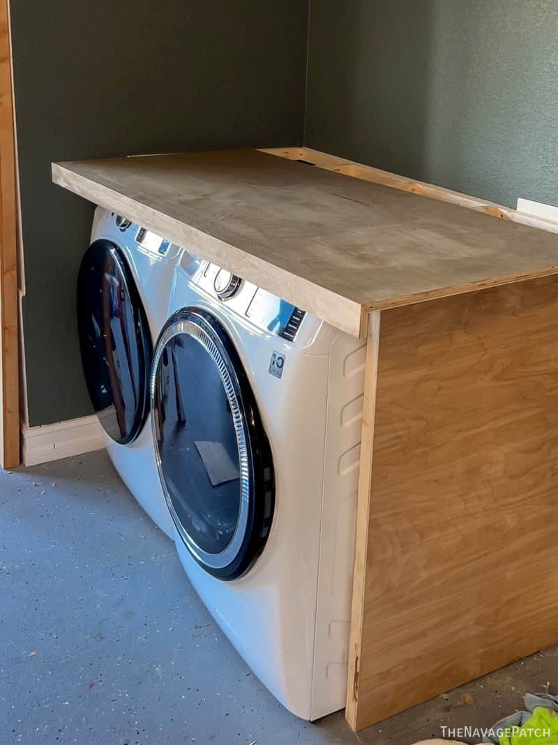 man staining a washer dryer enclosure