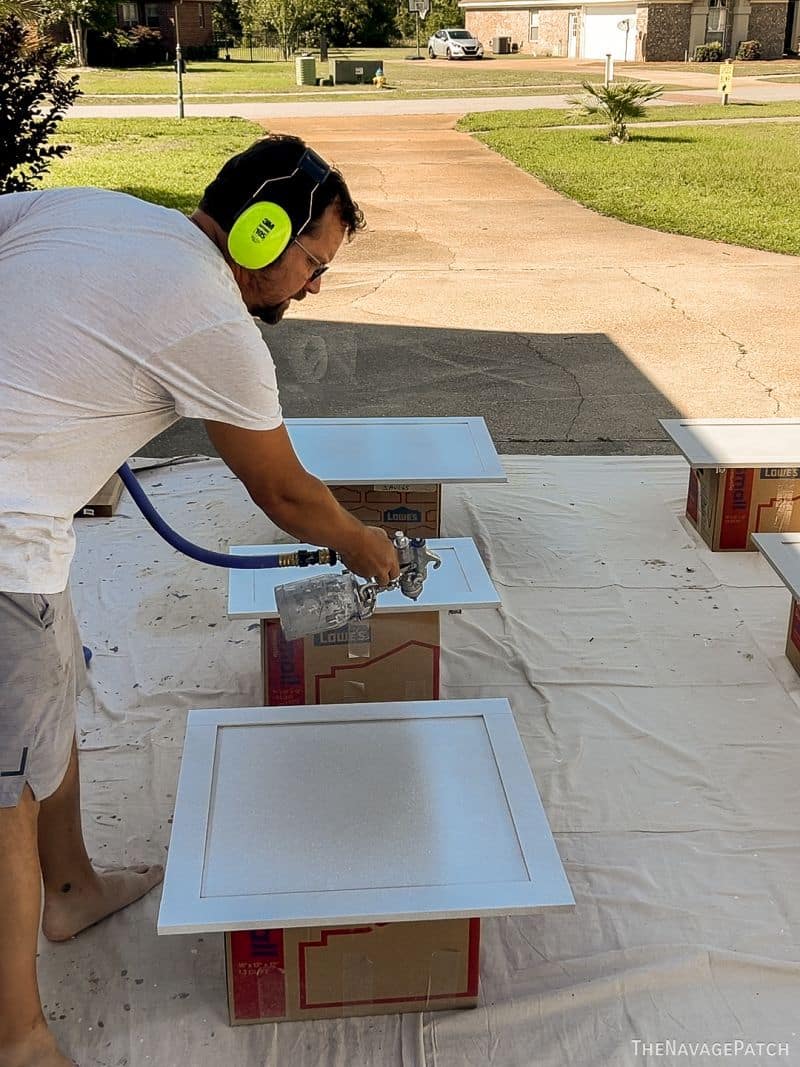 man priming cabinet doors