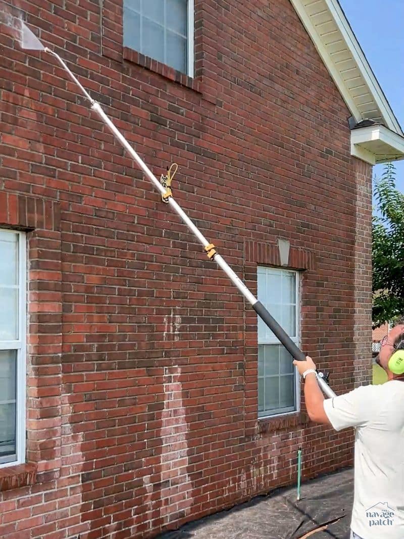 man power washing a brick house