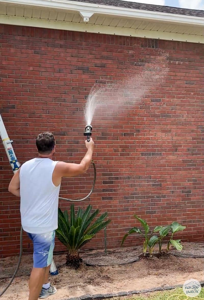 man hosing a brick house