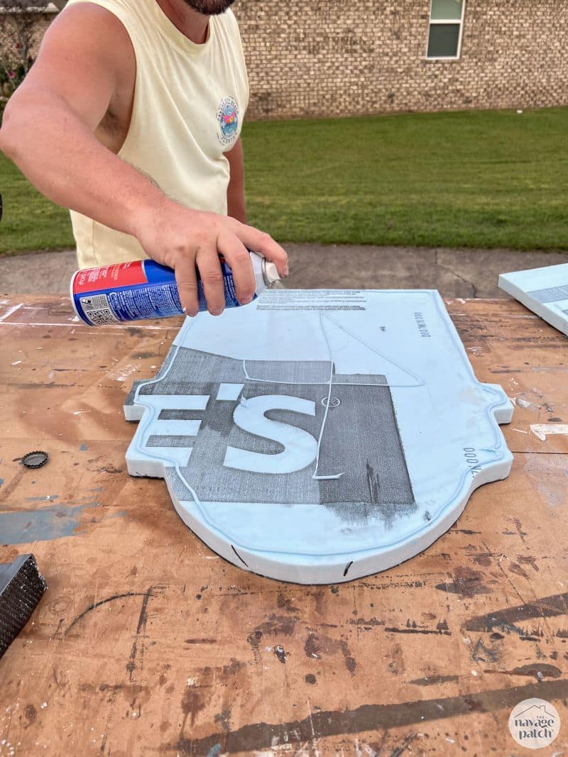 man spraying adhesive on foam cutout