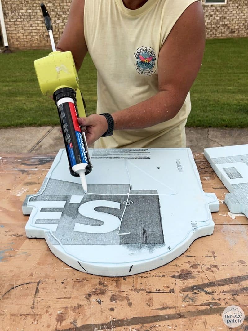 man putting foamboard adhesive onto a foam headstone cutout