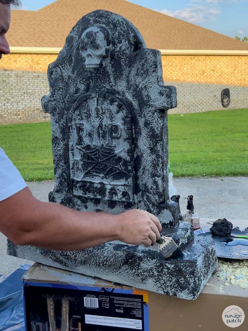 man painting tombstone