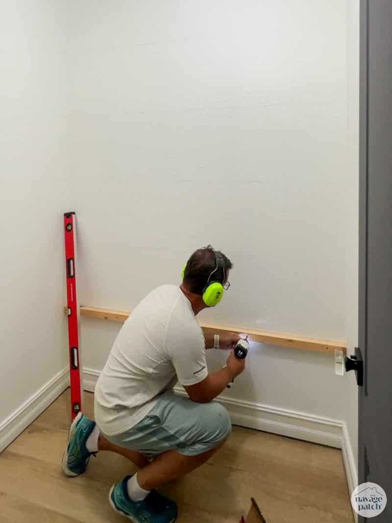 man installing shelf supports in a closet
