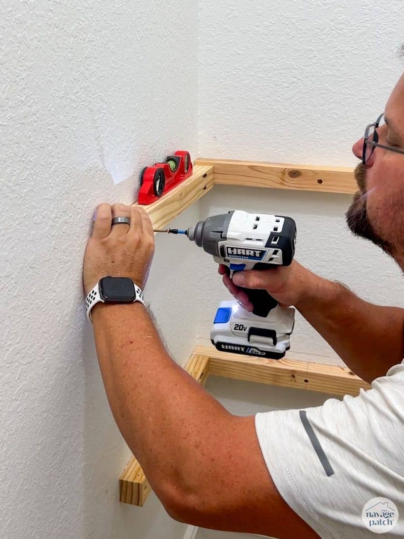 man installing shelf supports in a closet