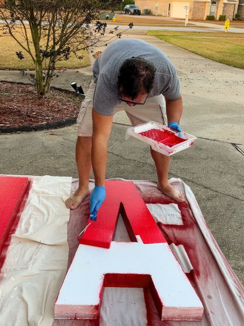 man painting big foam letters