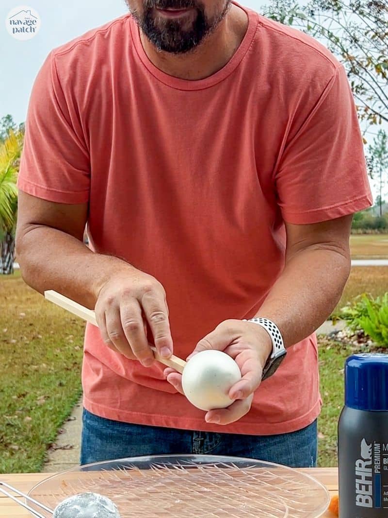 man putting a christmas ornament on a stick