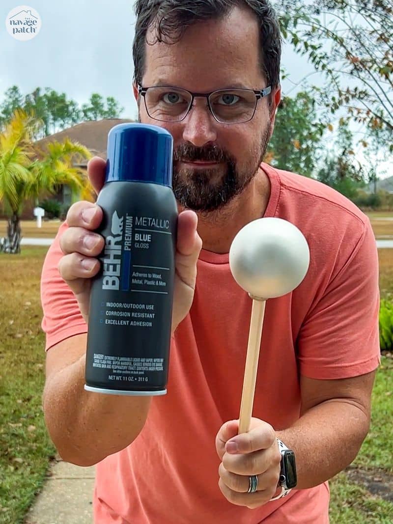 man holding a can of spray paint and a christmas ornament