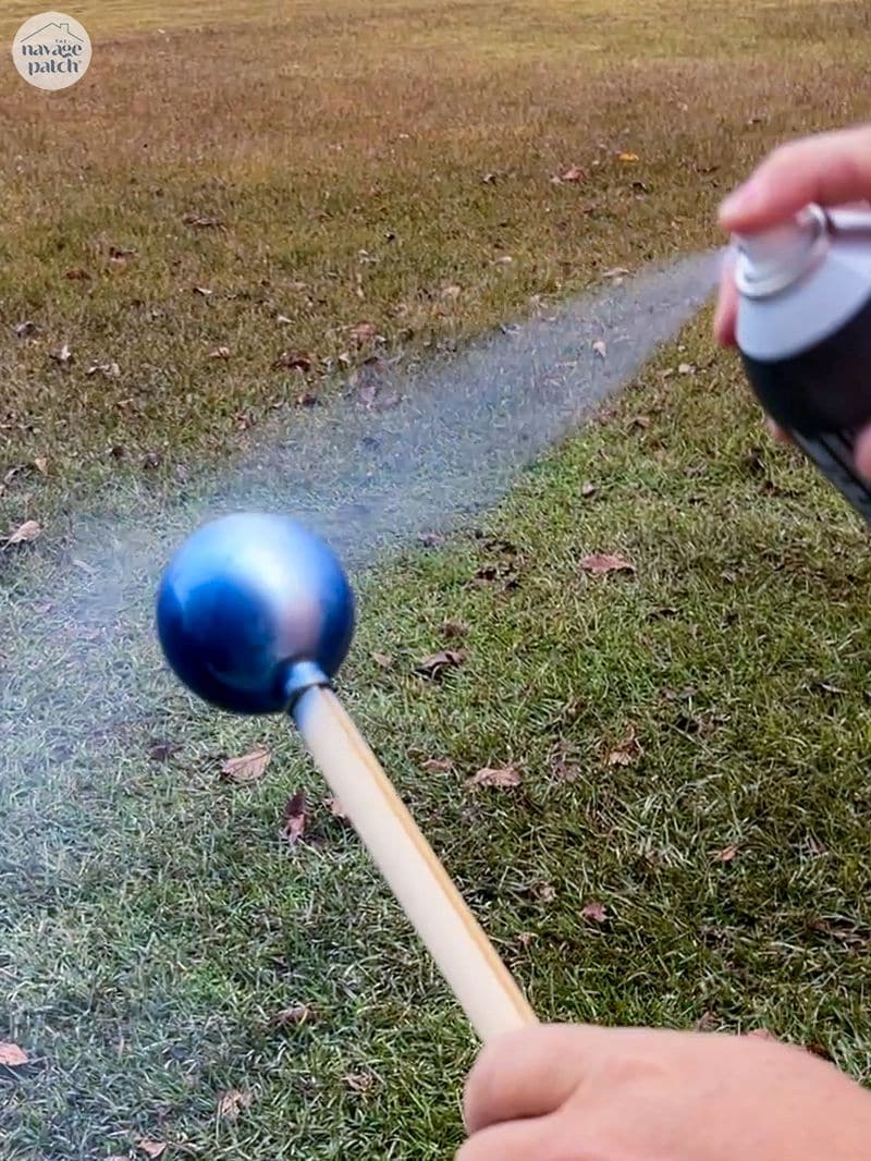 man spray painting an ornament ball blue