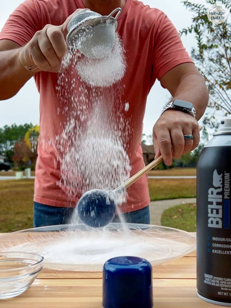 Man sprinkling baking soda on a christmas ornament