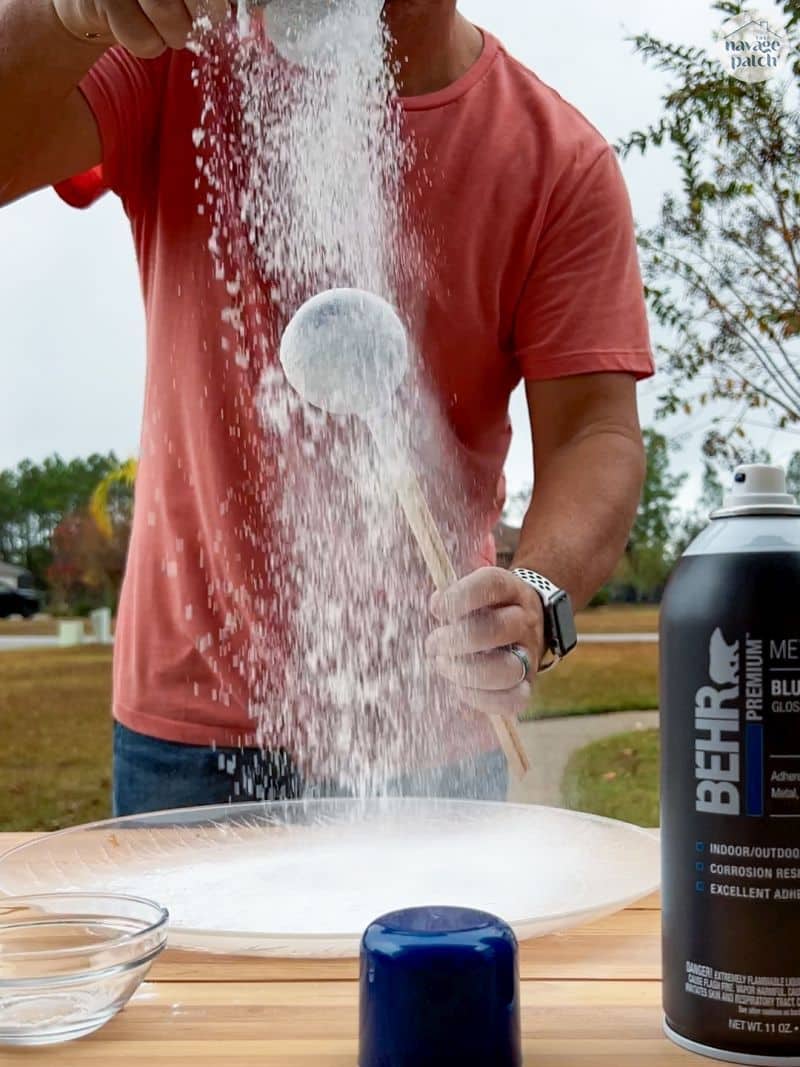 Man sprinkling baking soda on a christmas ornament