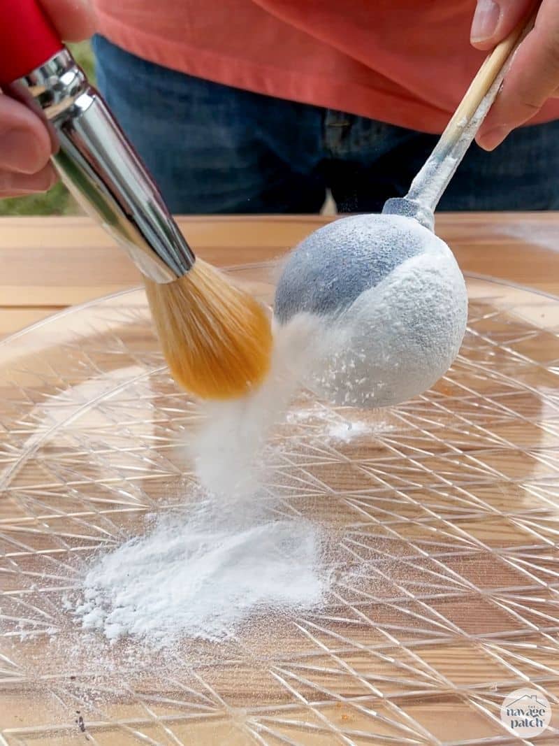 man brushing baking soda from an ornament