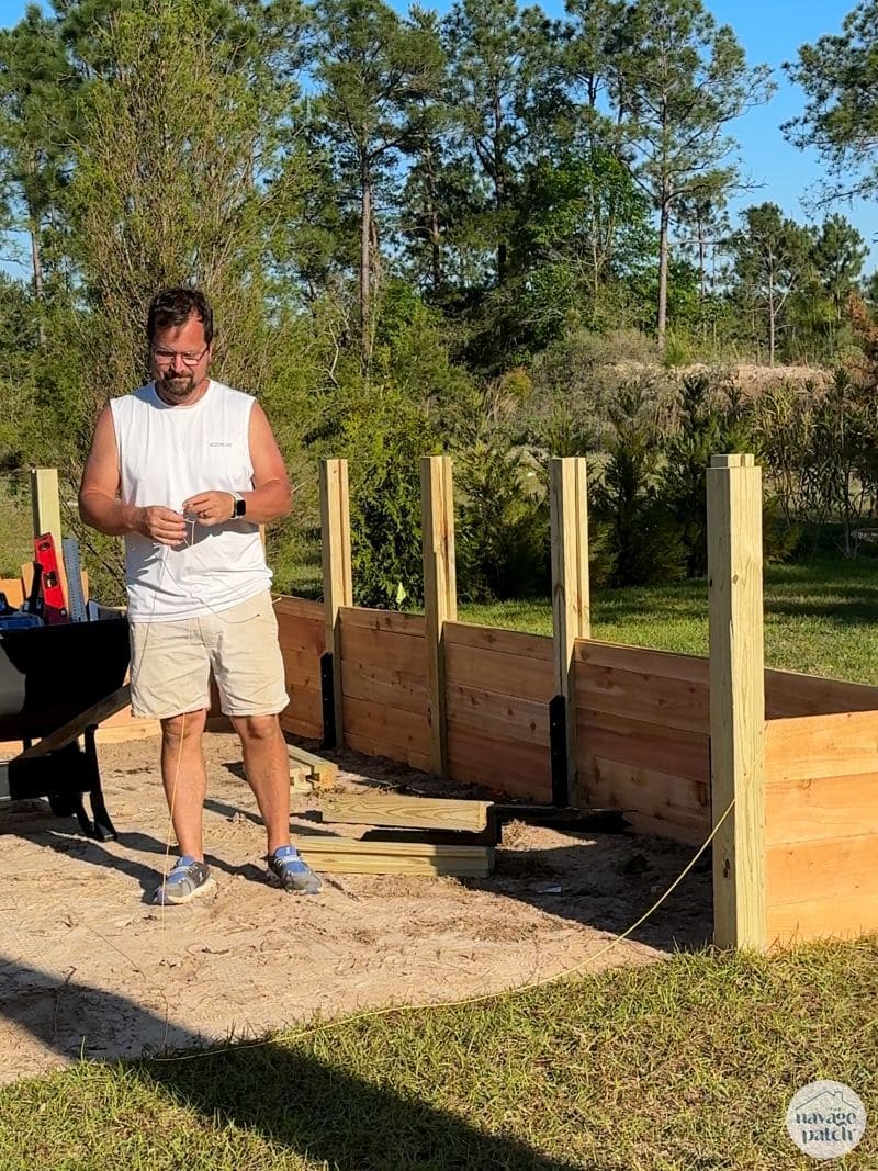 man standing next to a raised garden bed