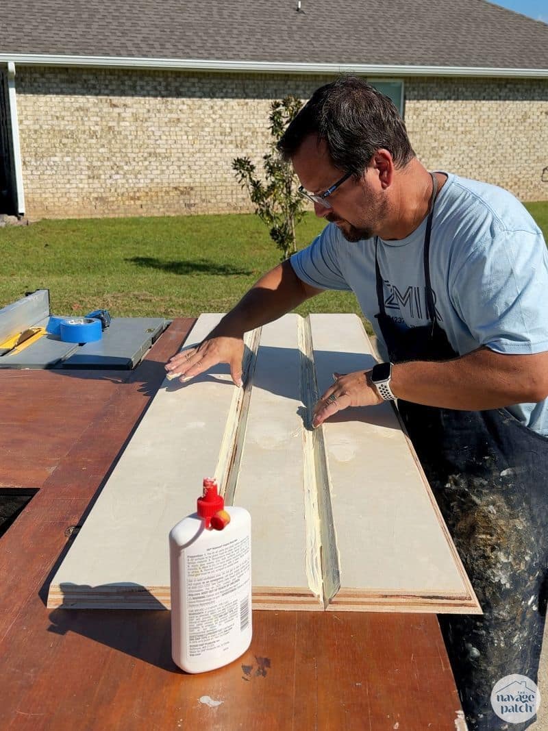 man gluing plywood into a diy fireplace mantel