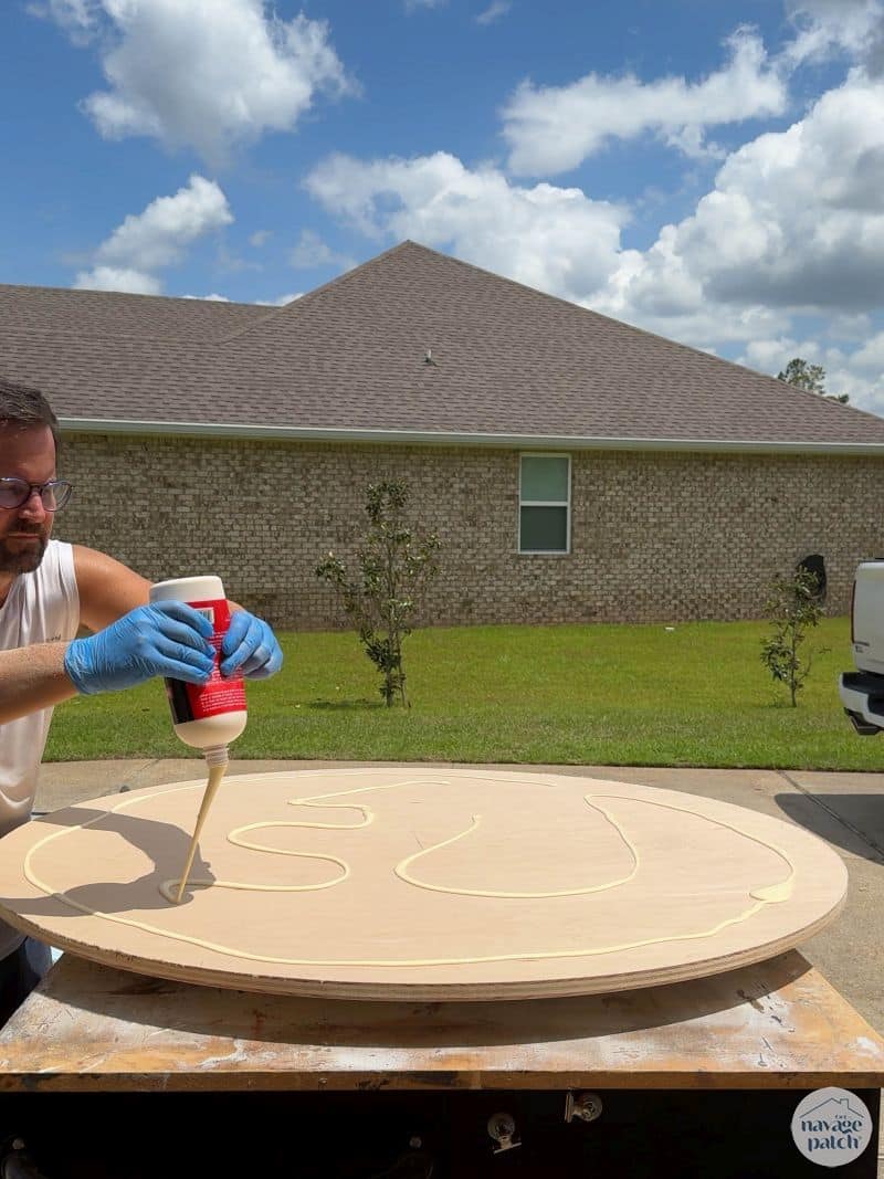 man gluing two plywood disks together
