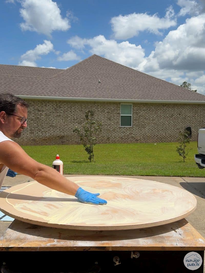 man gluing two plywood disks together