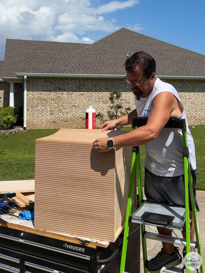 man gluing pole wrap on a cabinet