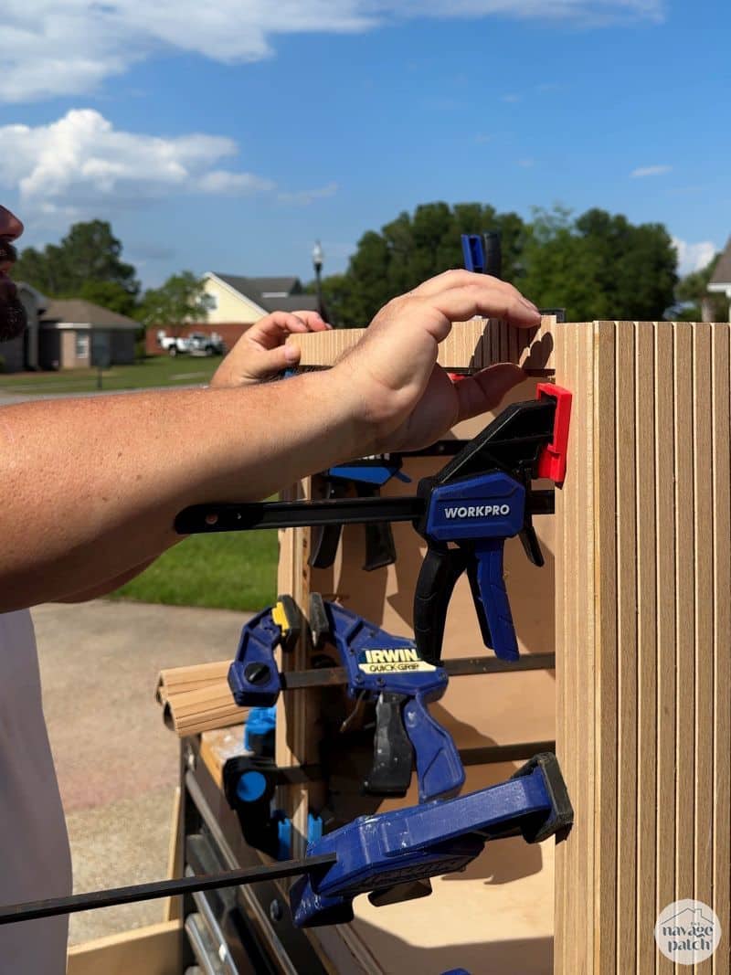 man gluing pole wrap on a cabinet
