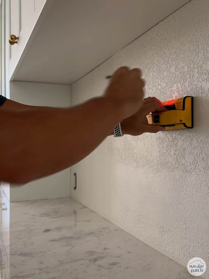 man marking studs on wall
