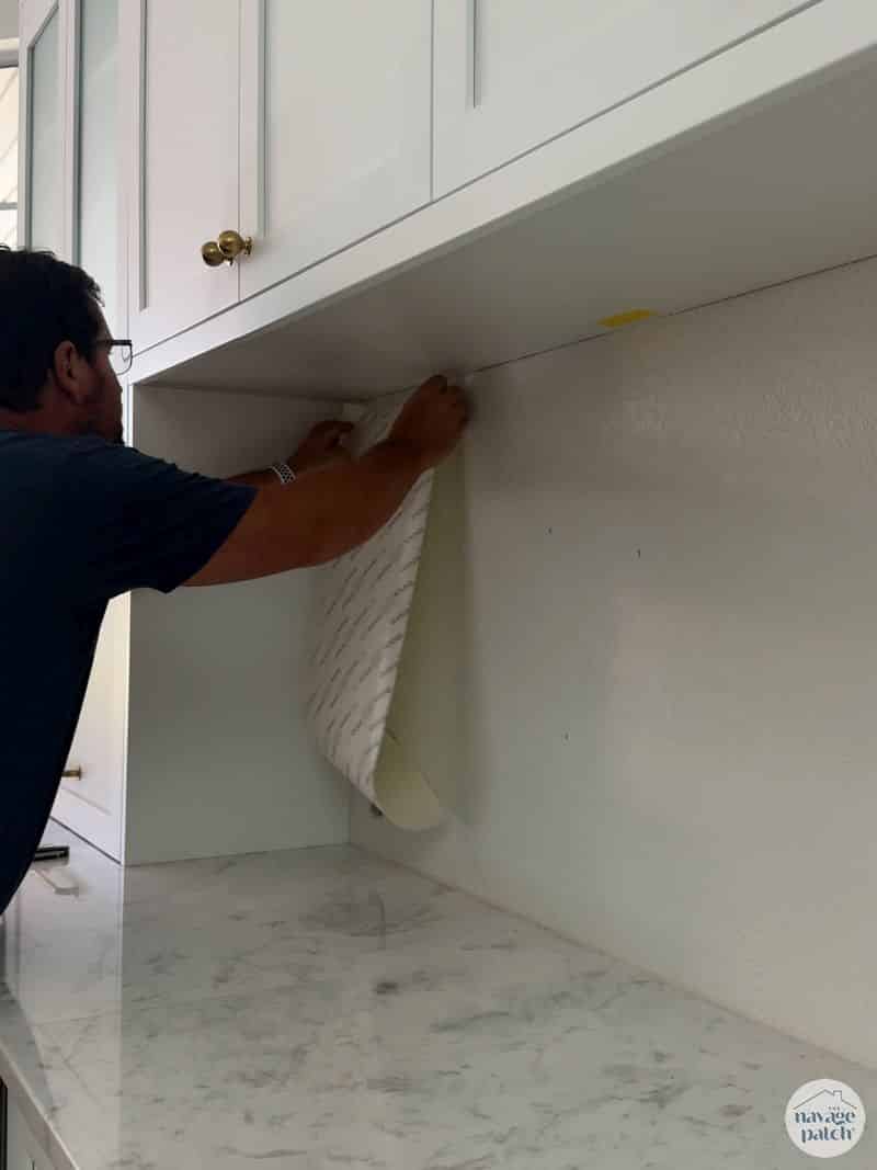man putting tile mat on wall
