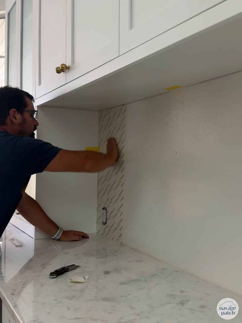 man putting tile mat on wall