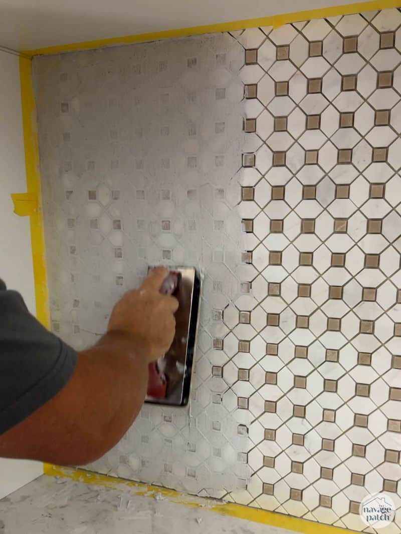 man grouting a tiled wall