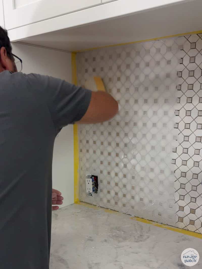 man wiping grout off a tiled wall
