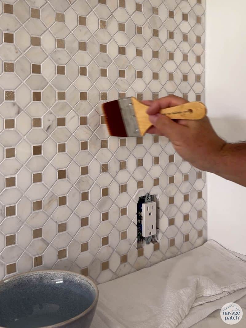 man putting grout sealant on tiled wall