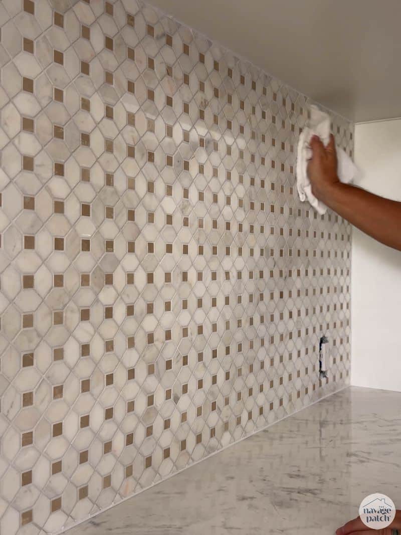 man putting sealant on grout