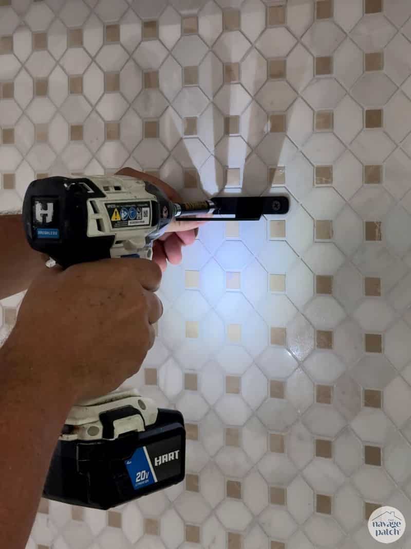 man attaching a bracket to a tiled wall