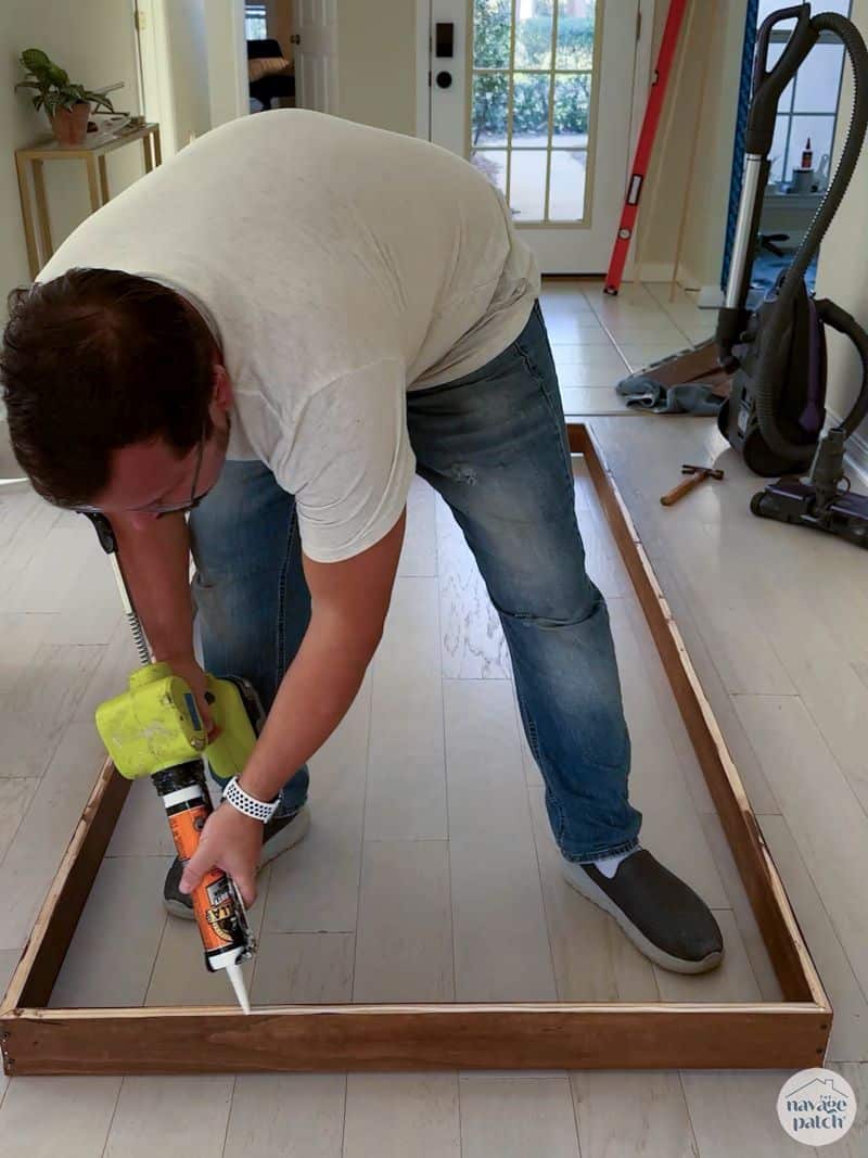 man putting adhesive on a frame