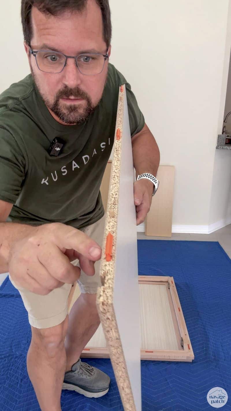 man holding a cabinet piece before assembly