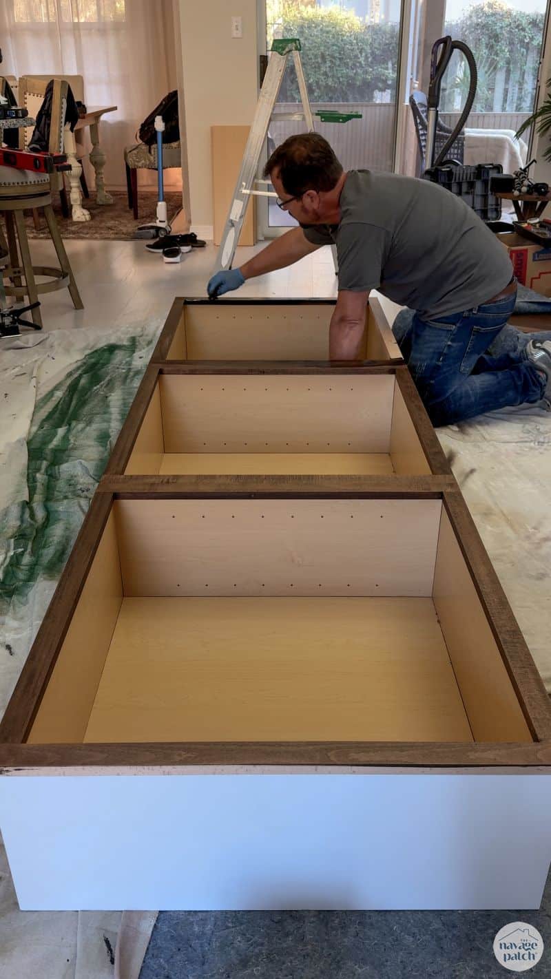 man staining cabinets on the floor