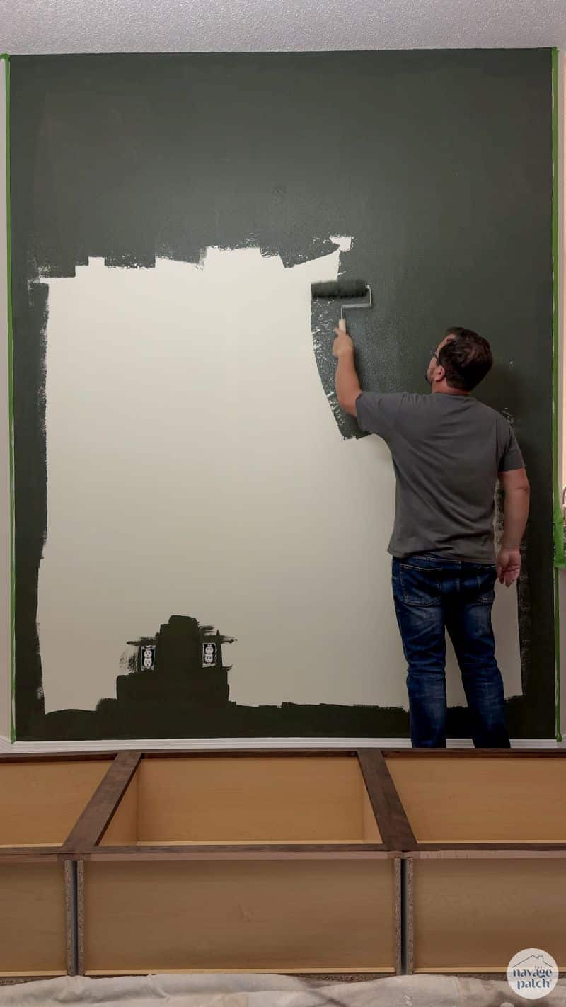 man painting a wall dark green