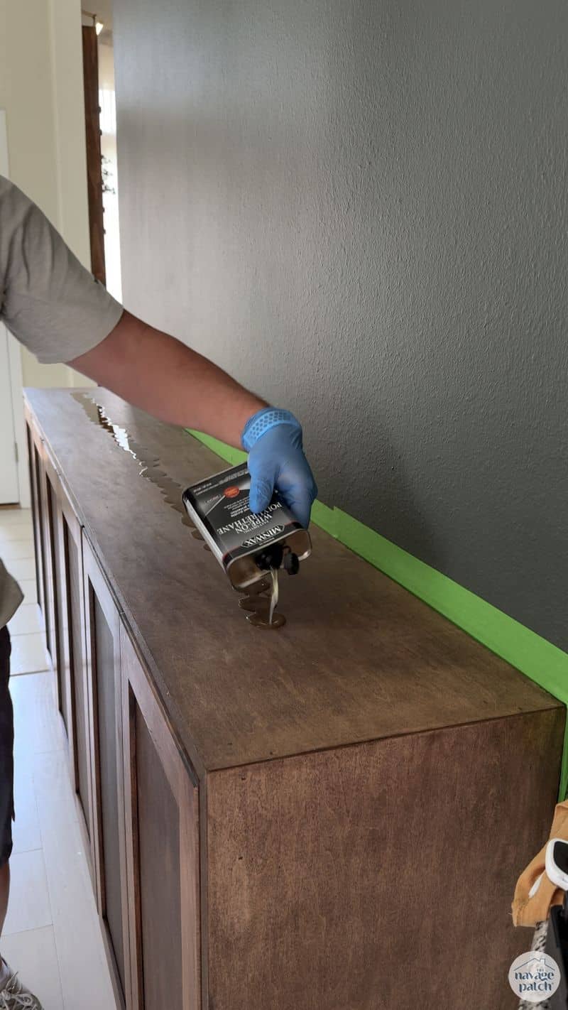 man applying polyurethane to a console table