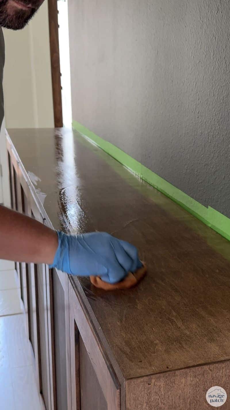 man applying polyurethane to a console table