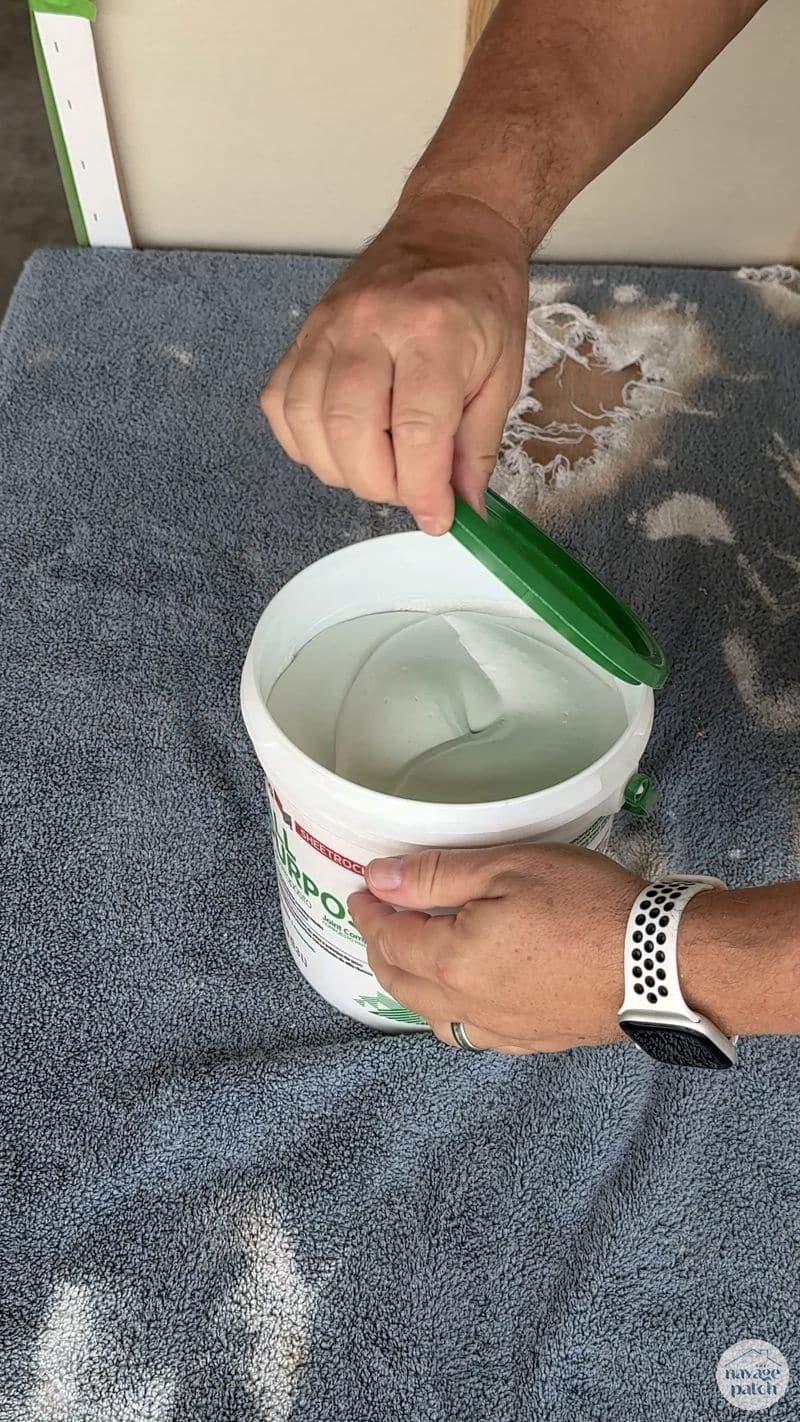 man opening a bucket of joint compound